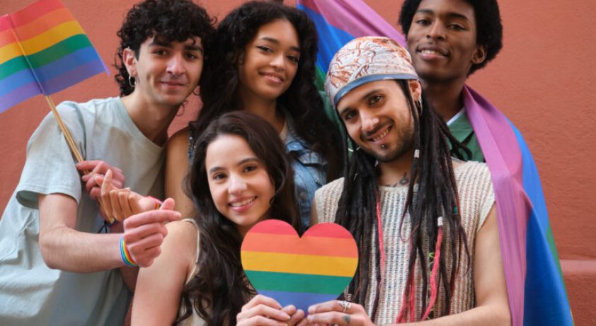 Young activists holding rainbow heart and LGBT flags promoting diversity and equality